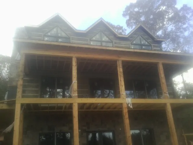 Dormers and porch framing on a large log home under construction — Roof Coating work by our crew in Mongo