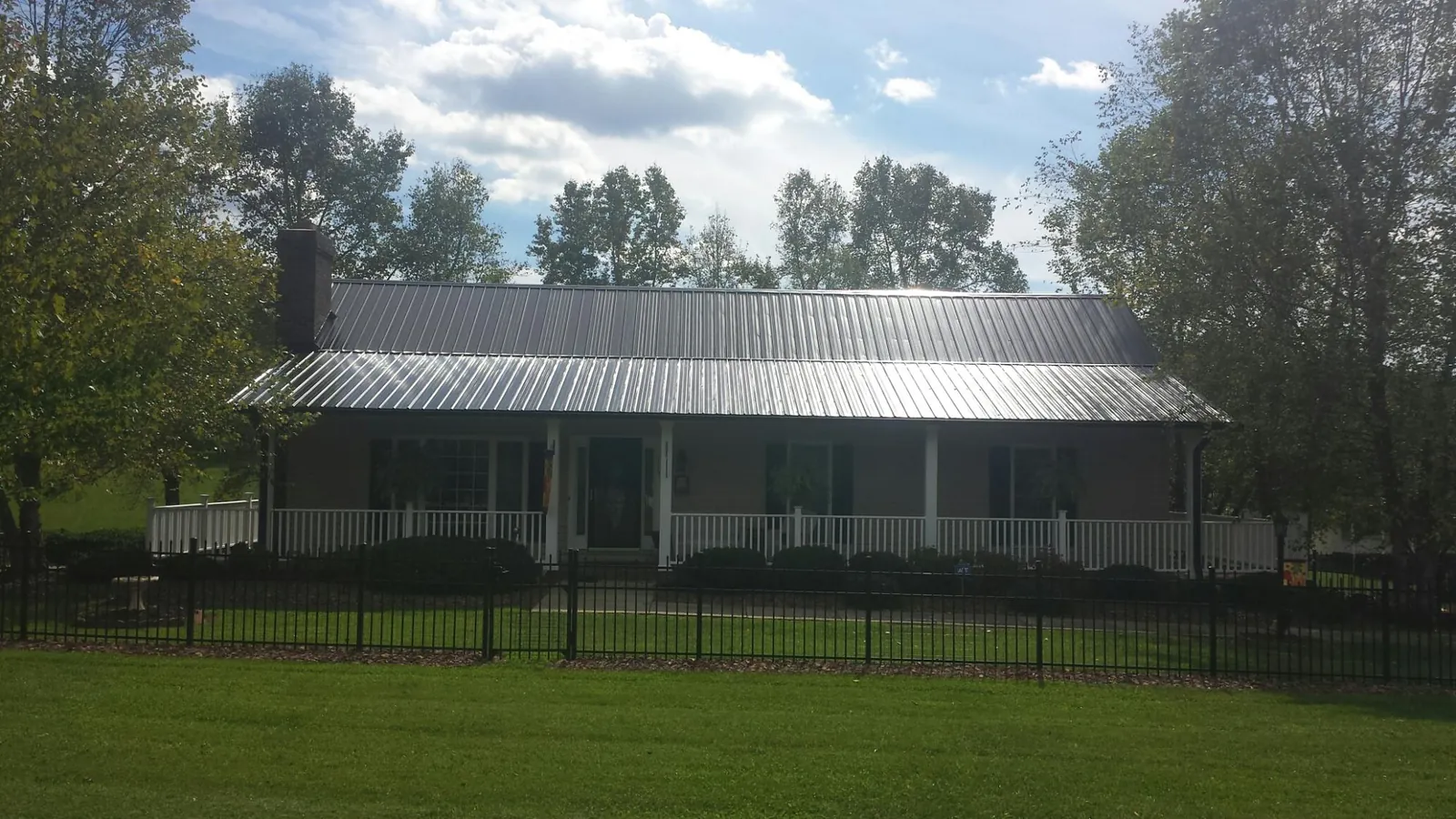 Gray metal roof on a brick ranch with a full width front porch — Gutter Guard Installation work by our crew in Mongo