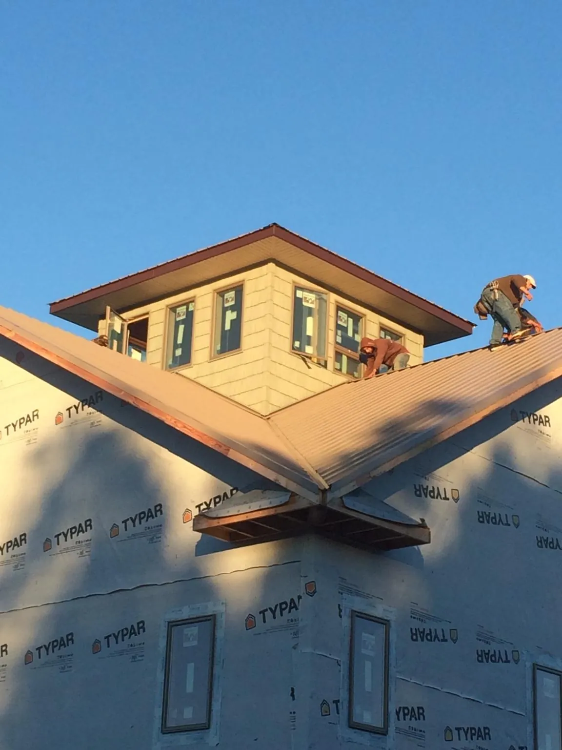 Roofers working around a rooftop cupola on a new metal roof at sunset — Roof Waterproofing in Mongo by Roofing Brothers